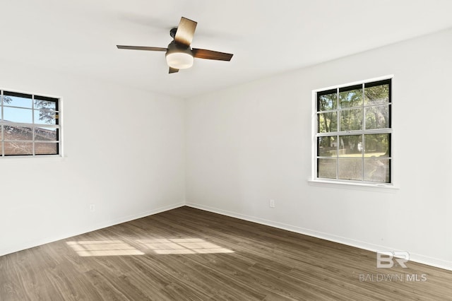 spare room with a healthy amount of sunlight, ceiling fan, and dark hardwood / wood-style floors