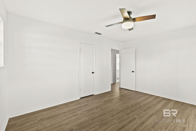 empty room with ceiling fan and dark hardwood / wood-style flooring