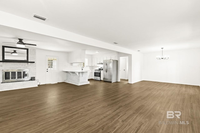 unfurnished living room featuring sink, ceiling fan with notable chandelier, dark hardwood / wood-style floors, and a fireplace