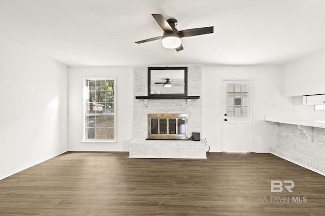 unfurnished living room with dark hardwood / wood-style flooring, a brick fireplace, and ceiling fan