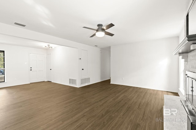 unfurnished living room featuring a brick fireplace, dark wood-type flooring, and ceiling fan