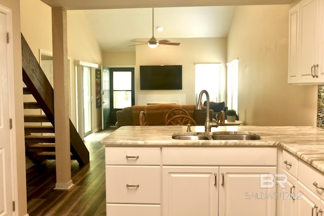 kitchen with sink, plenty of natural light, lofted ceiling, and white cabinetry