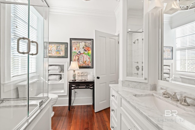 full bathroom featuring shower / bath combination with glass door, hardwood / wood-style floors, toilet, vanity, and ornamental molding