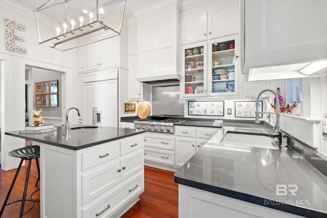 kitchen featuring sink, an island with sink, stainless steel gas stovetop, and paneled built in refrigerator