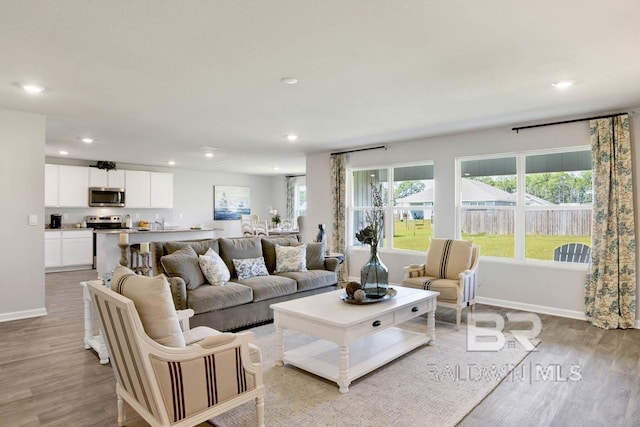 living room with baseboards, light wood-style flooring, and recessed lighting