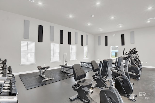 exercise room with baseboards, a healthy amount of sunlight, and recessed lighting