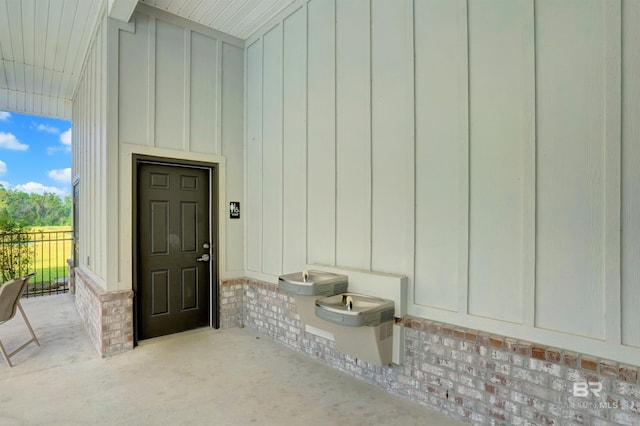 entrance to property with board and batten siding, brick siding, and fence