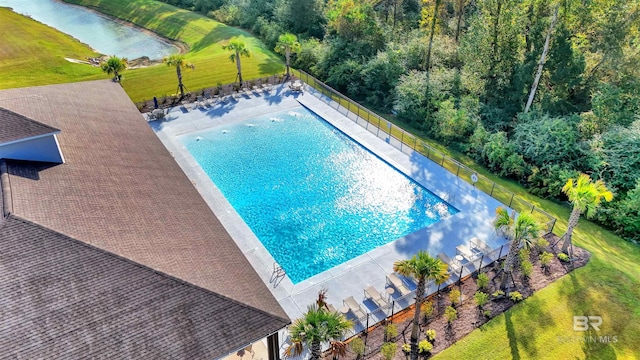 pool featuring a water view, fence, a yard, and a patio area