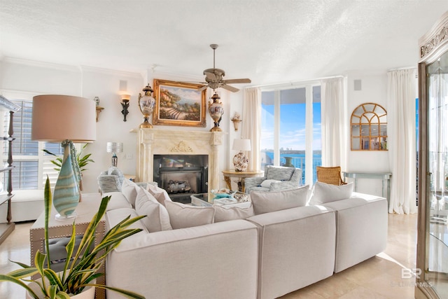 living room with a premium fireplace, crown molding, a textured ceiling, and ceiling fan