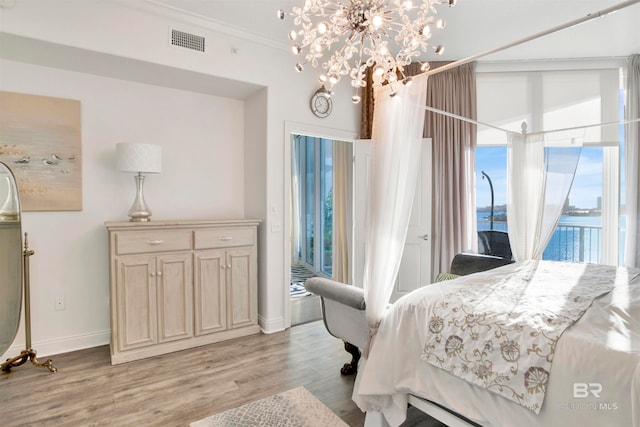 bedroom with ornamental molding, a water view, and light hardwood / wood-style floors