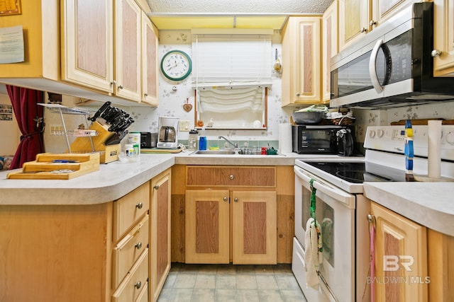 kitchen with light tile patterned floors, white range with electric cooktop, sink, and kitchen peninsula