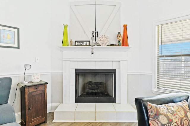 living area featuring a tiled fireplace and light hardwood / wood-style floors