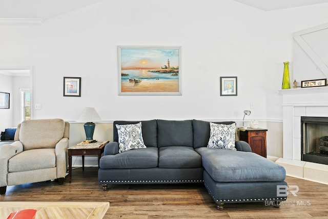 living room featuring hardwood / wood-style floors, crown molding, and a tile fireplace