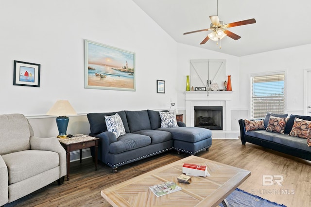 living room with hardwood / wood-style flooring, ceiling fan, a fireplace, and vaulted ceiling