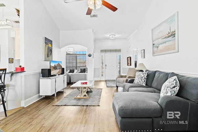 living room with ceiling fan, ornamental molding, light hardwood / wood-style flooring, and a high ceiling