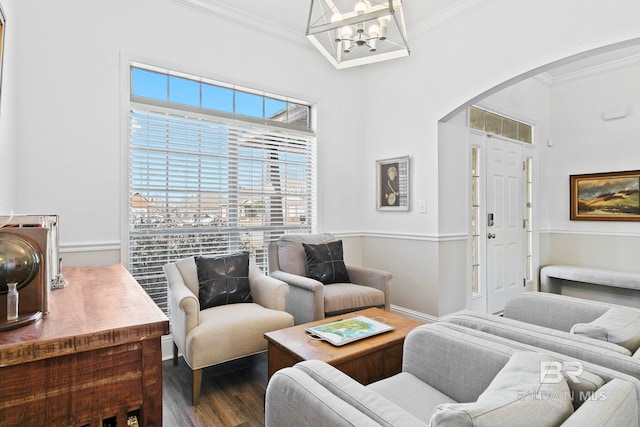 living room featuring an inviting chandelier, ornamental molding, and wood-type flooring