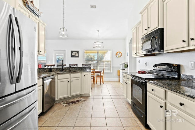 kitchen featuring cream cabinets, decorative light fixtures, light tile patterned floors, and black appliances