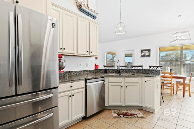 kitchen featuring stainless steel appliances, sink, light tile patterned floors, and decorative light fixtures