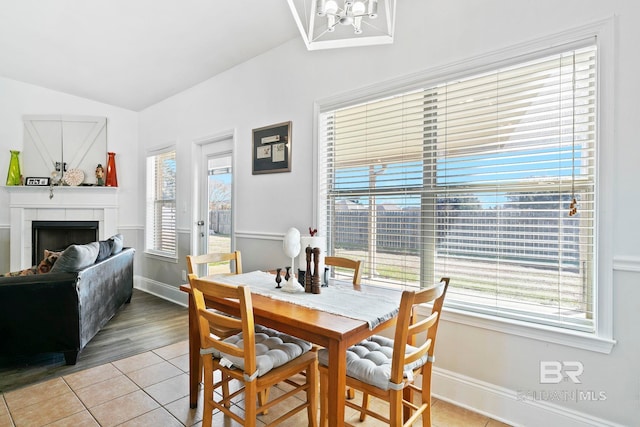 dining space featuring lofted ceiling, a chandelier, light tile patterned floors, and a fireplace