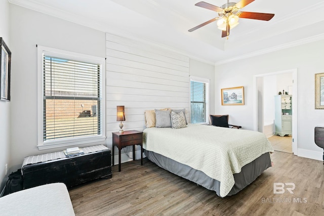 bedroom with connected bathroom, crown molding, a tray ceiling, ceiling fan, and hardwood / wood-style floors