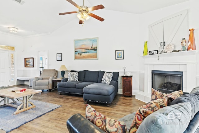 living room with crown molding, a tile fireplace, ceiling fan, wood-type flooring, and vaulted ceiling