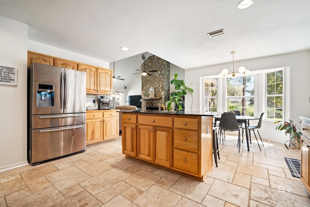 kitchen featuring ceiling fan with notable chandelier, dark countertops, stone tile floors, recessed lighting, and stainless steel fridge