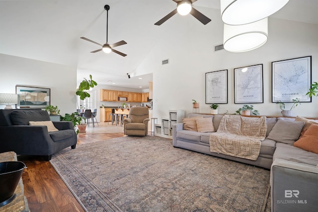 living room featuring ceiling fan, visible vents, high vaulted ceiling, and wood finished floors