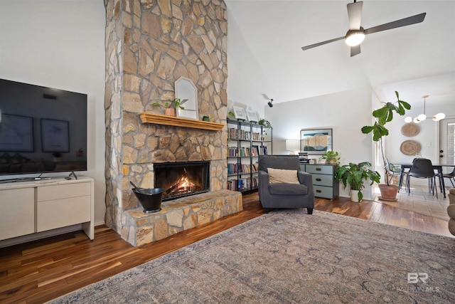 living room with a stone fireplace, wood finished floors, and a towering ceiling