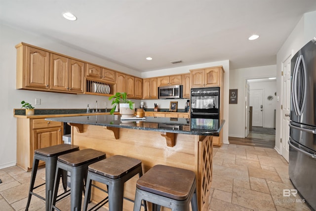 kitchen with dark stone counters, stone tile floors, recessed lighting, and appliances with stainless steel finishes