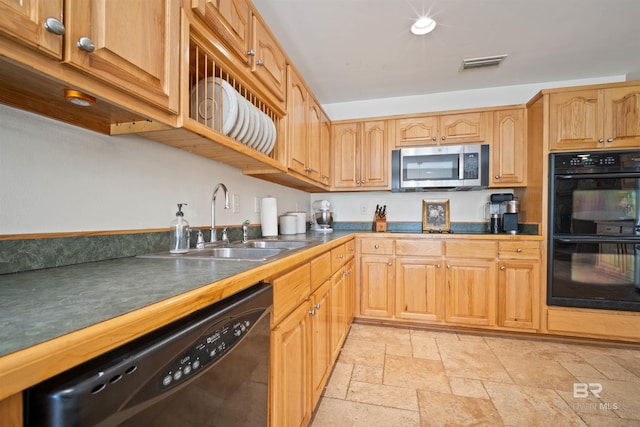 kitchen featuring dark countertops, visible vents, stone tile floors, black appliances, and a sink