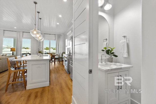 kitchen with light wood-style flooring, a kitchen breakfast bar, light countertops, and a sink