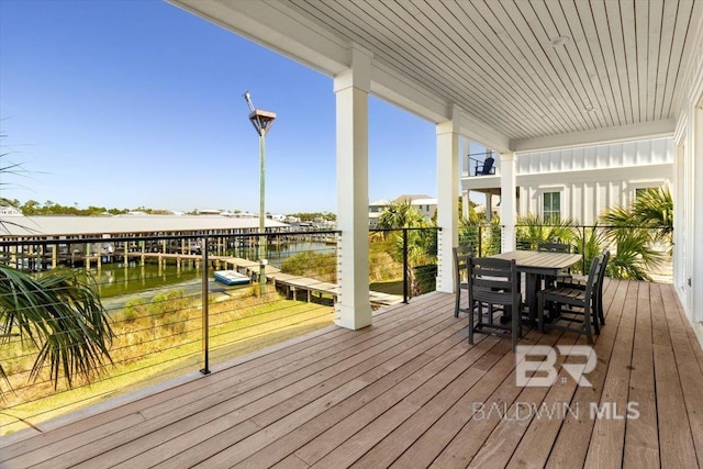 wooden terrace featuring outdoor dining space and a water view