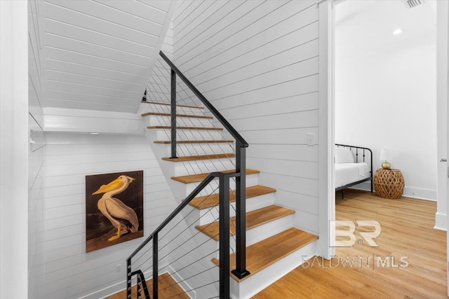 staircase featuring wood finished floors and baseboards