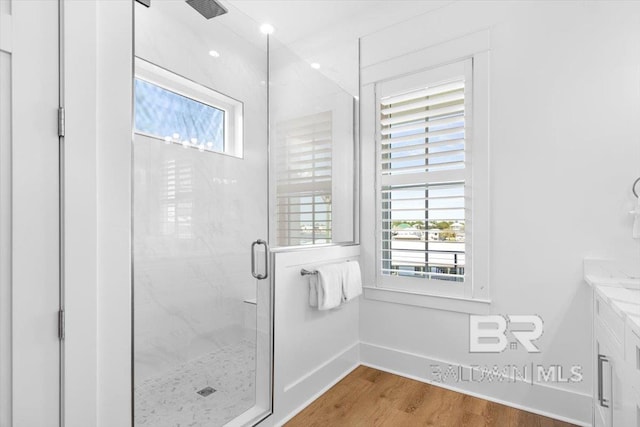 bathroom featuring wood finished floors, a stall shower, a wealth of natural light, and baseboards