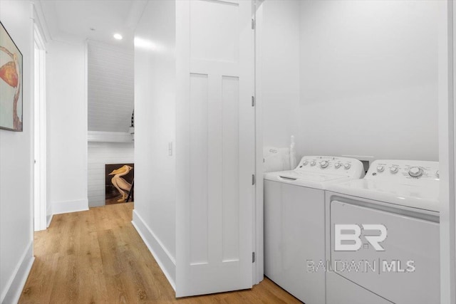 laundry area featuring laundry area, baseboards, light wood-type flooring, and washer and clothes dryer