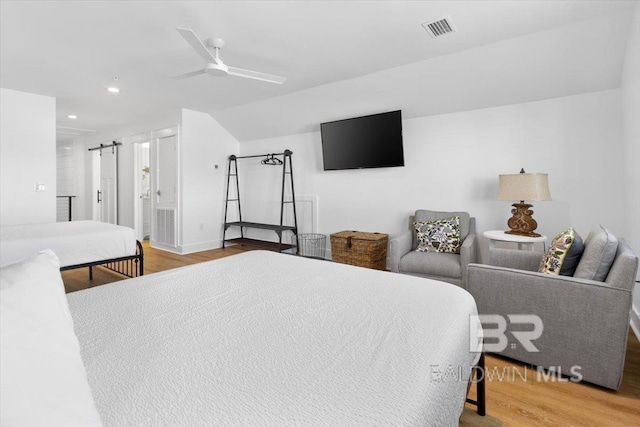 bedroom with wood finished floors, visible vents, recessed lighting, a barn door, and connected bathroom