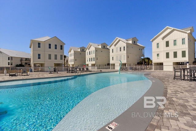 community pool featuring a patio area, fence, and a residential view