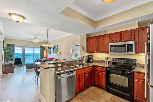 kitchen with ornamental molding, dark stone counters, ceiling fan with notable chandelier, and stainless steel appliances