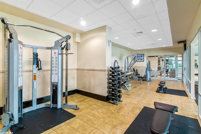 exercise room with light tile flooring and a drop ceiling