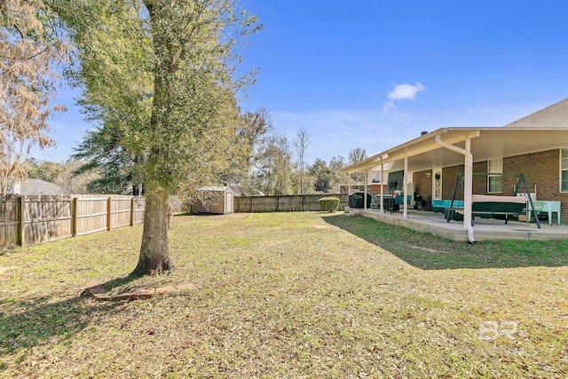 view of yard with a storage unit, a patio, an outbuilding, and a fenced backyard