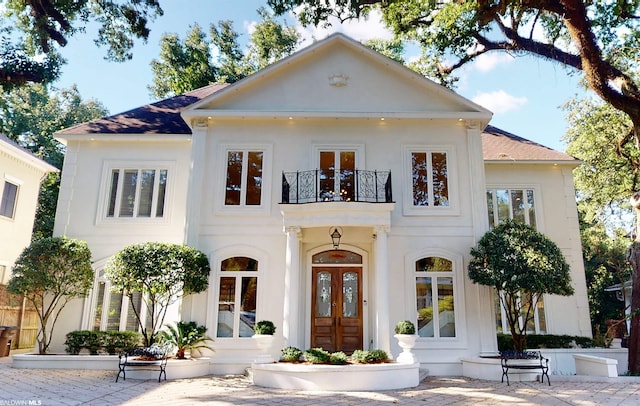 neoclassical / greek revival house featuring french doors, a balcony, and a patio area