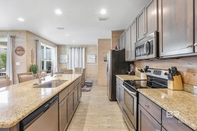 487 E 1st Ave Unit F, Gulf Shores, AL 36542 - kitchen with visible vents, wood walls, a sink, stainless steel appliances, and plenty of natural light