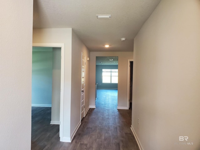 hall with dark wood-type flooring and a textured ceiling