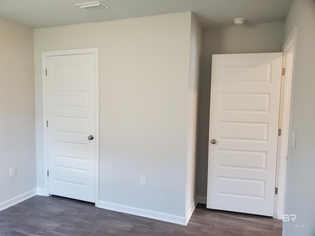 unfurnished bedroom with dark hardwood / wood-style flooring