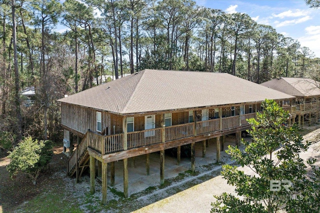 back of property featuring driveway and a shingled roof