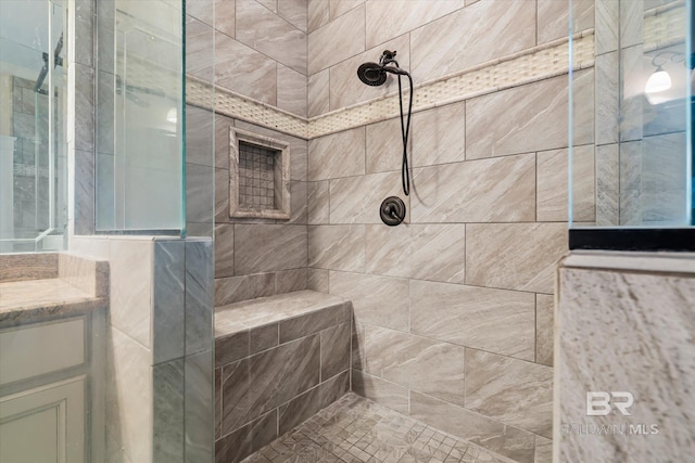 bathroom with tiled shower and vanity