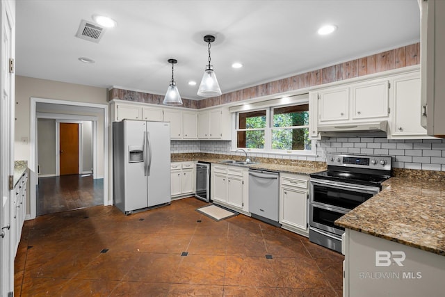 kitchen with appliances with stainless steel finishes, dark stone counters, sink, white cabinetry, and hanging light fixtures