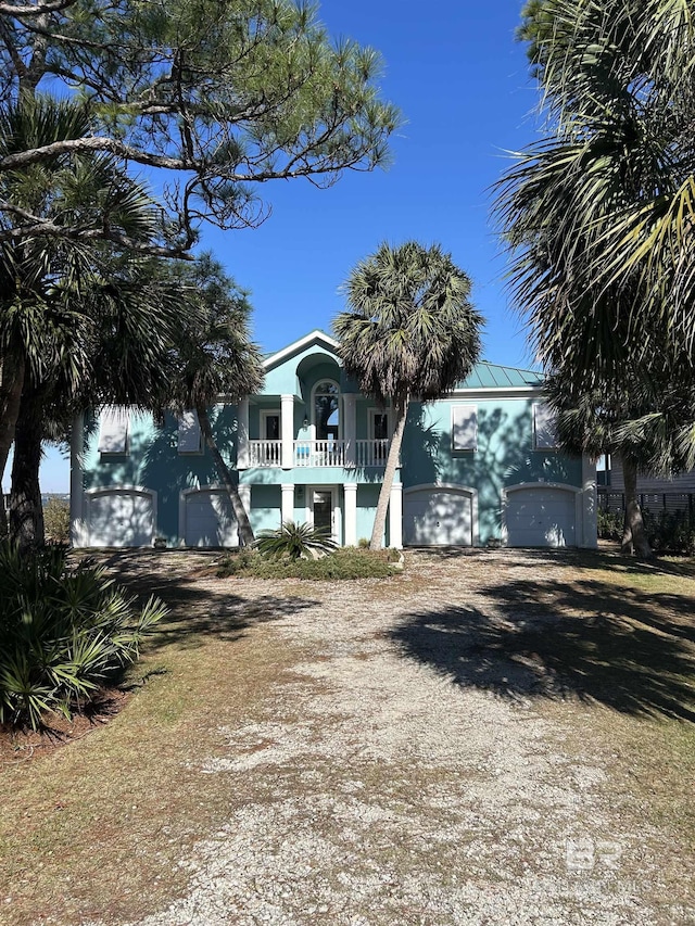 view of front of house featuring a garage, driveway, a balcony, metal roof, and stucco siding