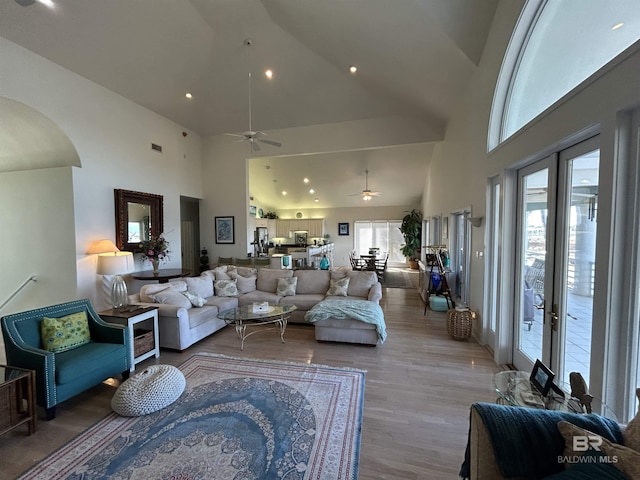 living area featuring high vaulted ceiling, arched walkways, wood finished floors, and french doors