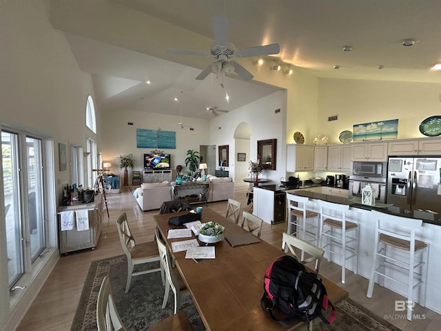 dining area with arched walkways, ceiling fan, light wood-type flooring, and visible vents